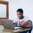 A black guy operating laptop